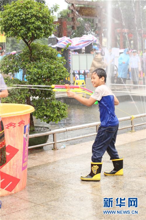 小孩子拿着水枪兴致勃勃地朝别人滋水.新华网 纪惊鸿 摄