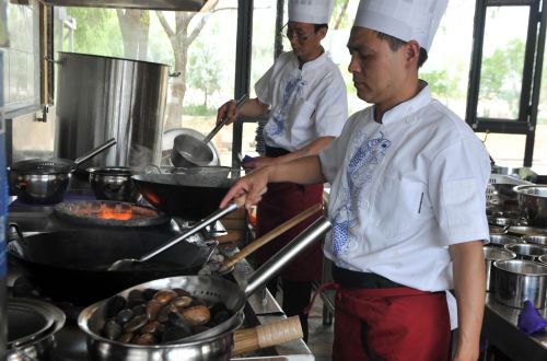 <p>6月3日，鱼府厨师正在将滚石放入油锅中加热。刘泉龙摄</p>