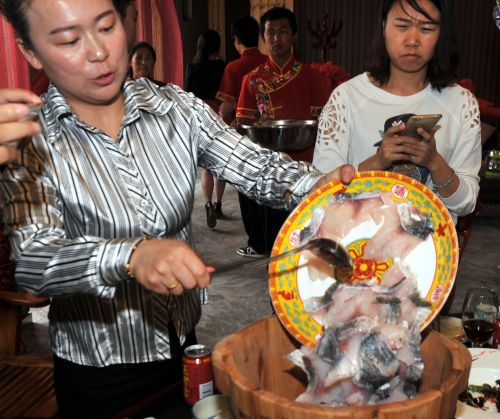 6月3日，鱼府服务员将生态鱼放入滚石木盆中准备让游客品尝。刘泉龙摄_副本