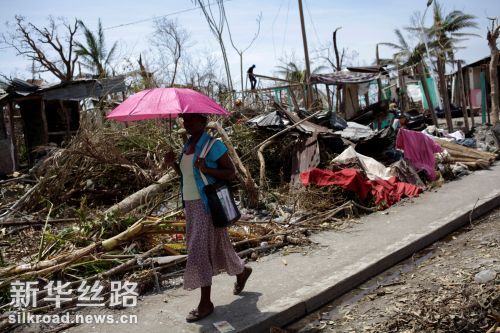 10月10日，在海地莱昂格莱，一名女子走过被飓风“马修”摧毁的房屋 新华社　路透