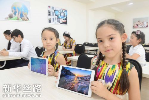 6月21日，在乌兹别克斯坦塔什干第59中学，两名乌兹别克斯坦女学生在华为公司捐赠的智慧教室内展示教学设备 记者沙达提摄