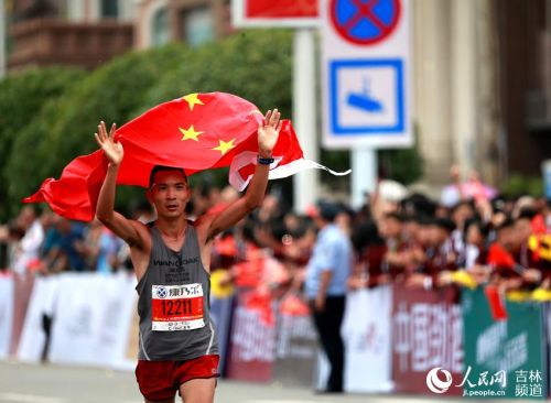 选手李子成举旗通过终点，成为国内参赛选手中的第一名。（吉马供图）