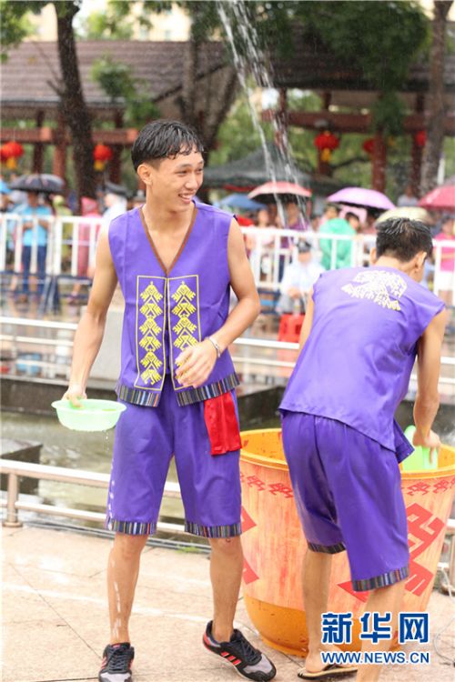 穿着黎族苗族服饰的阿哥端着一盆水瞄准对象泼洒“圣水”。新华网 纪惊鸿 摄