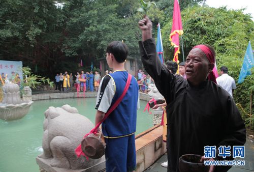 “圣水”取毕,长老用树叶蘸着“圣水”为众人祈福。新华网 纪惊鸿 摄