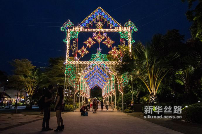 图4 游客们经过装设在滨海湾花园擎天树丛下的巨型圣诞灯饰（新华社发 符传威摄）