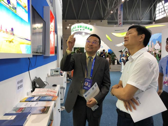 图为重庆市铜梁区区委常委、副区长张洪伟（右）在了解新华丝路产品和服务