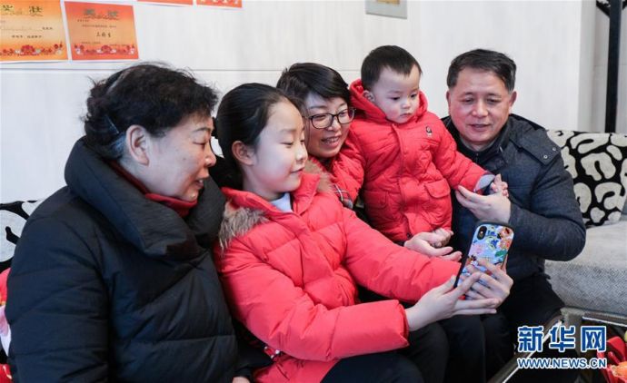 在四川绵阳市家中，李玲（中）与家人通过手机跟远航的丈夫曹玉强提前拜年（1月25日摄）。 新华社发（朱琳琳 摄）